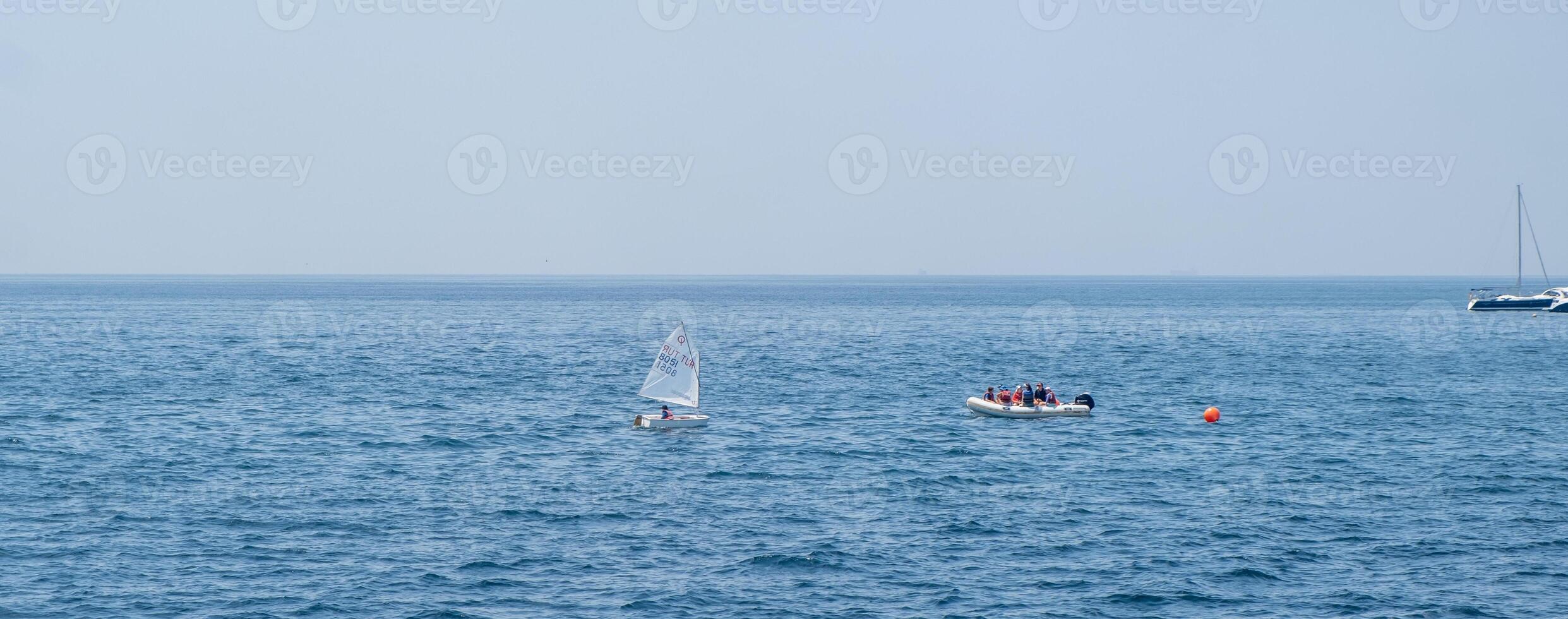 Sailing and recreational boating on a calm day in the open ocean with distant sailboats visible on the horizon photo