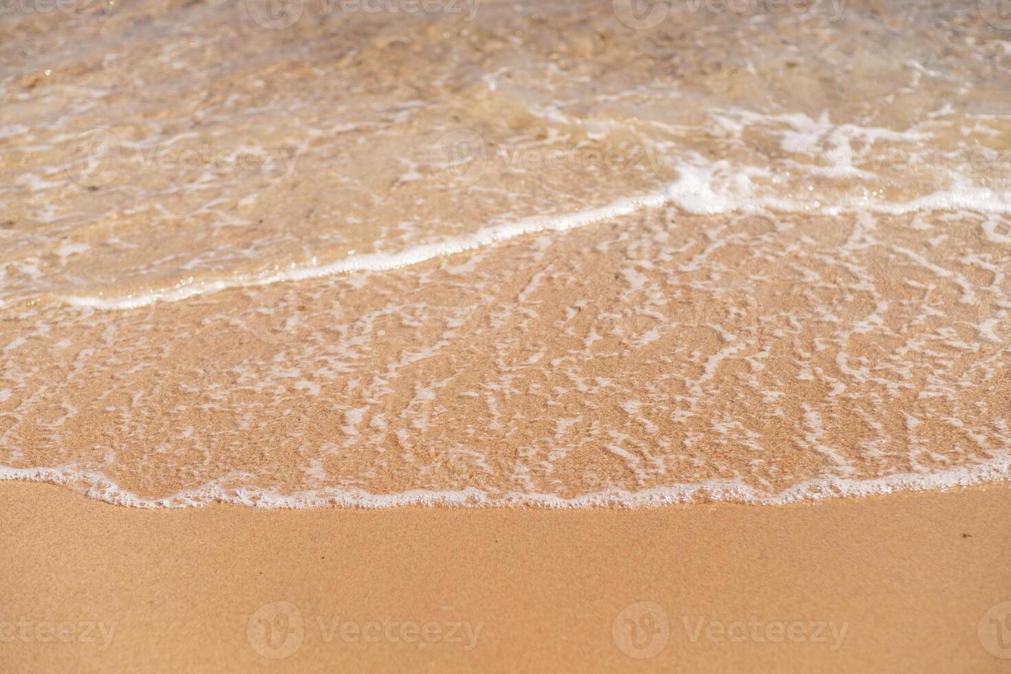 Soft waves wash gently onto a sandy beach in Egypt during a sunny afternoon in summer photo