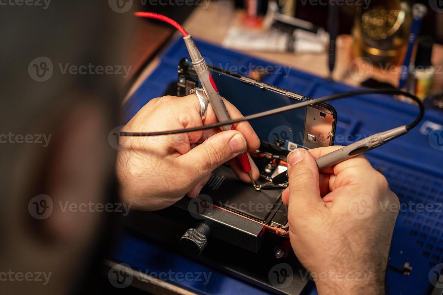 Technician repairing smartphone battery using soldering tools in a tech workshop during daylight hours photo