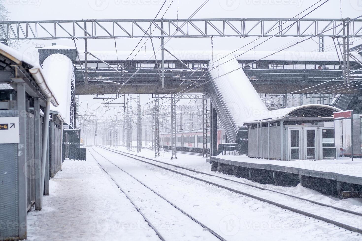 Snow covers the railway station creating a winter wonderland with empty tracks and falling flakes in the early morning light photo
