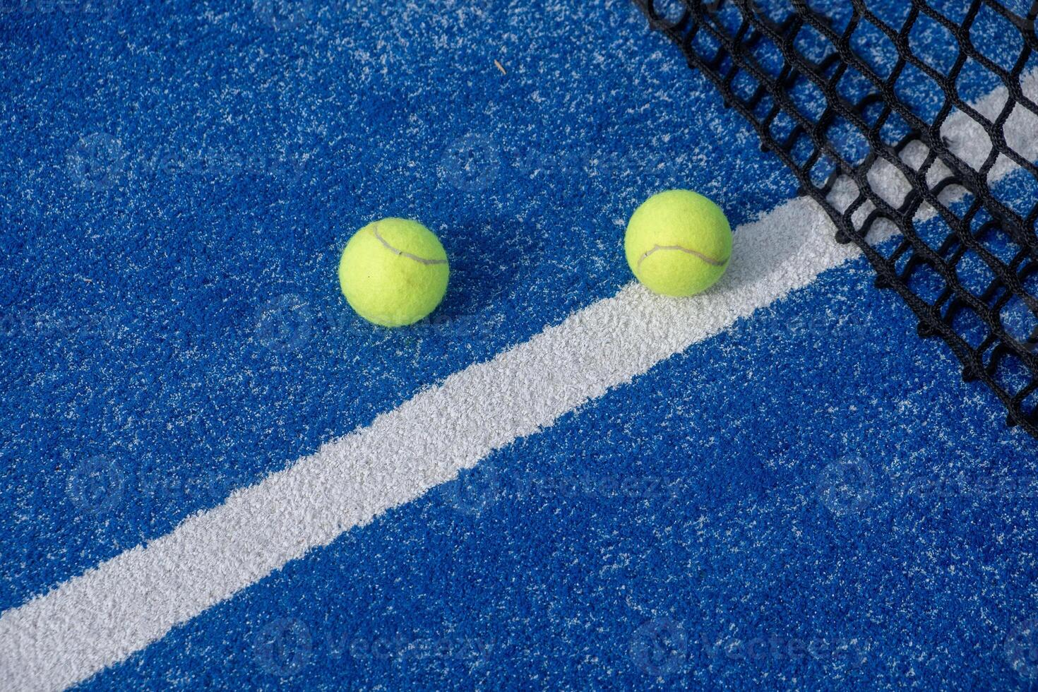 two padel balls near the net in a blue paddle tennis court, background for racket sport concept photo