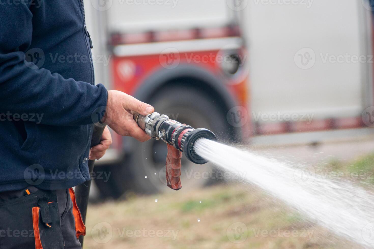 firefighter extinguishing smoldering wood structure with hose photo