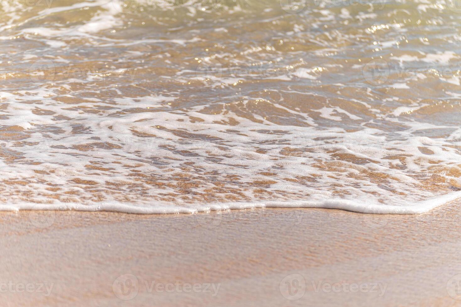 calm ocean waves meeting sandy shore, detailed coastal texture sand closeup view photo