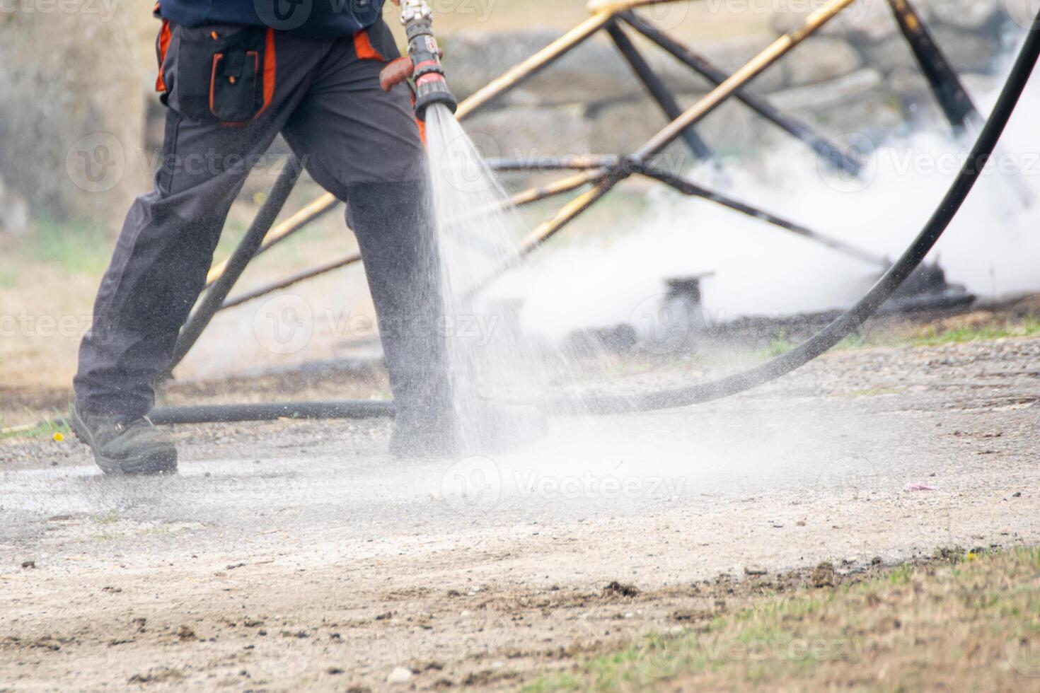 emergency personnel cooling down fire remnants with water photo