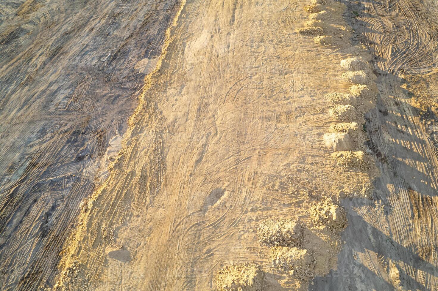 raw soil and rock heaps on barren land, piles of dirt and rocks on construction site.Top view by drone, aerial image photo