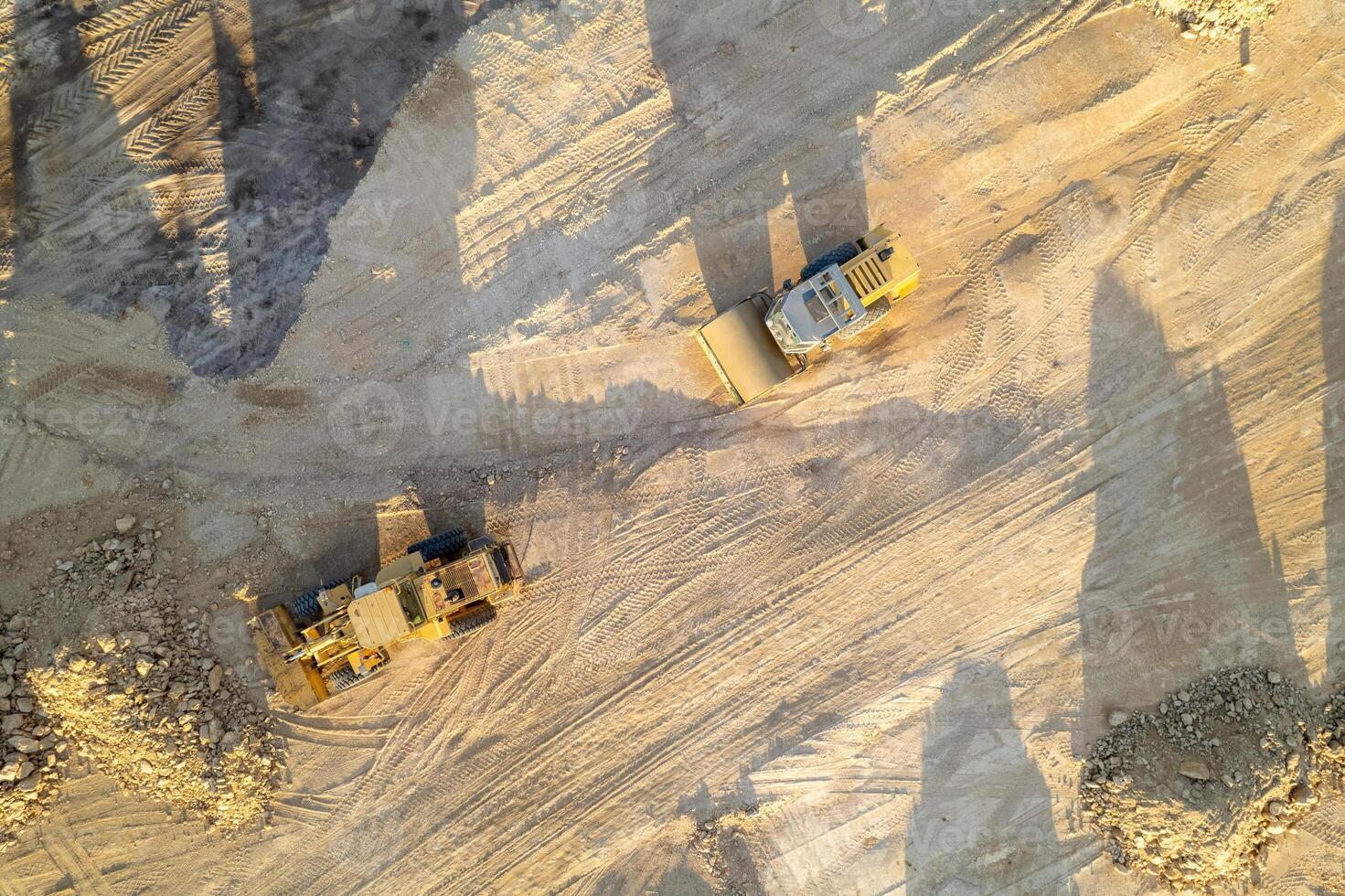 industrial machinery working on a construction site, aerial perspective of excavators and dirt piles. photo
