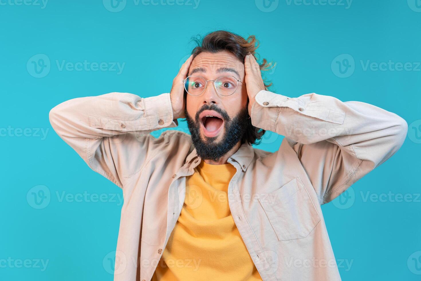Surprised Man Expressing Shock and Disbelief with His Hands Raised on His Head in Awe photo
