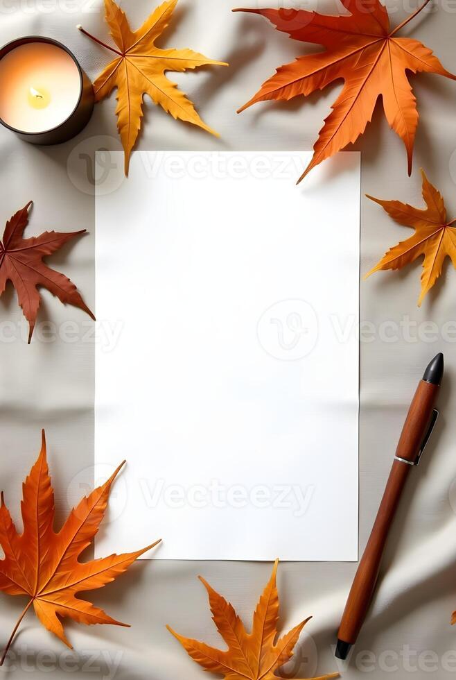 Blank paper with autumn leaves, pen and a candle on a soft fabric background photo