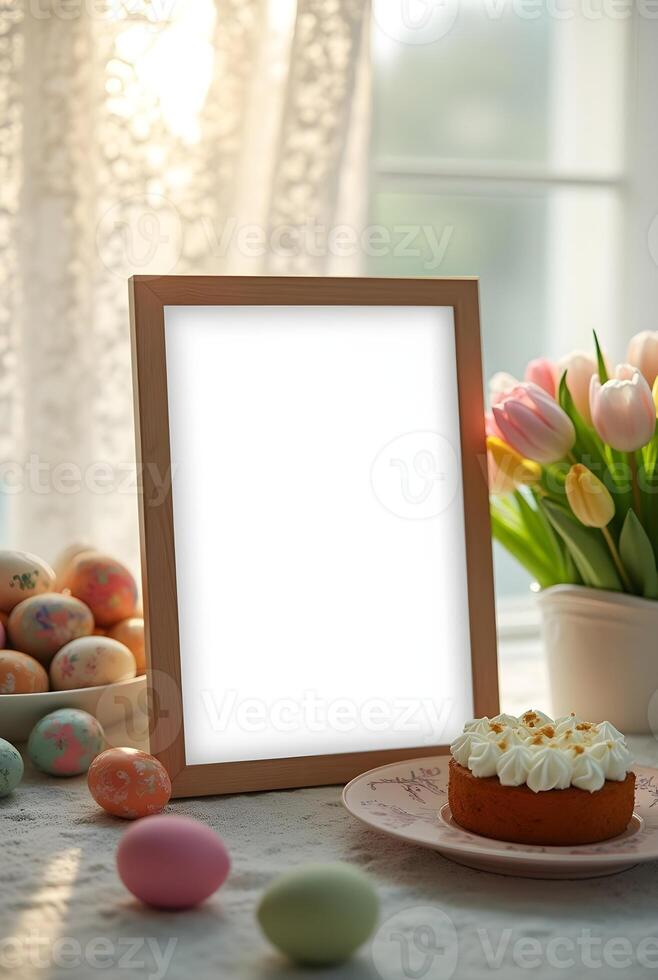 A blank wooden frame sits on a table adorned with Easter eggs, a festive Easter cake, and a vase of tulips, creating a warm and inviting springtime scene photo