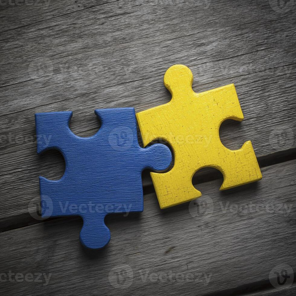 Two puzzle pieces, one blue and other yellow, connect on wooden surface, symbolizing unity and collaboration photo
