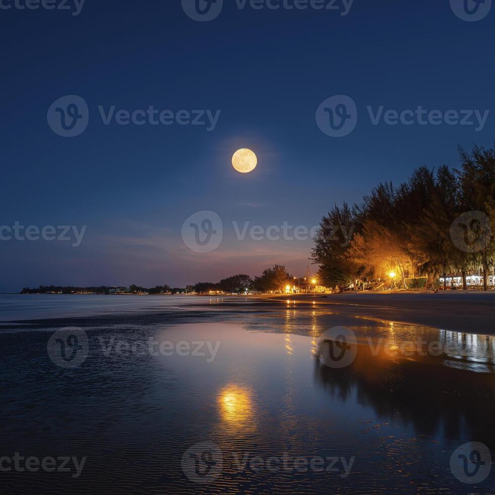 serene beach scene at night with full moon illuminating sky above calm sea, reflecting lights from shore photo