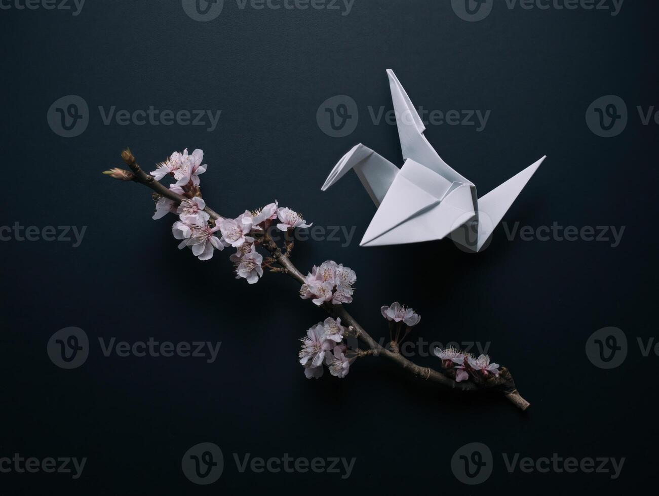 White origami paper bird with flower branch looks delicate and fragile against dark background, evoking sense of peace and simple beauty photo