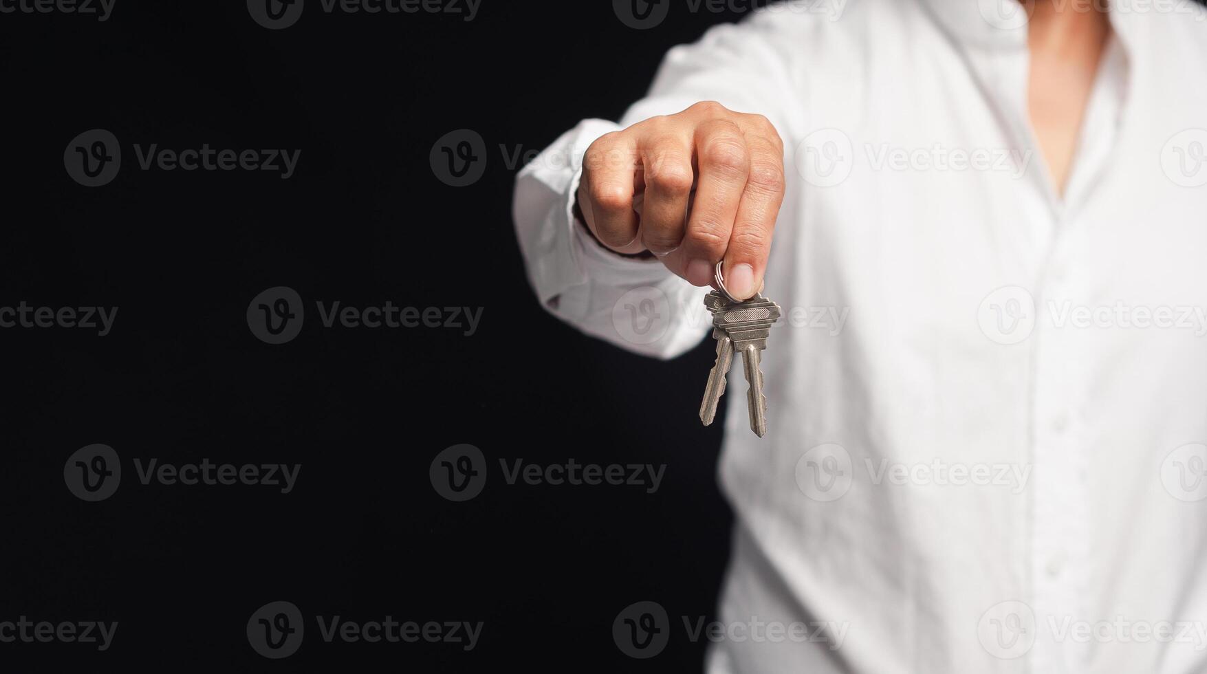 Hand of a businessman or real estate agent with keys from a new house hanging on the finger photo