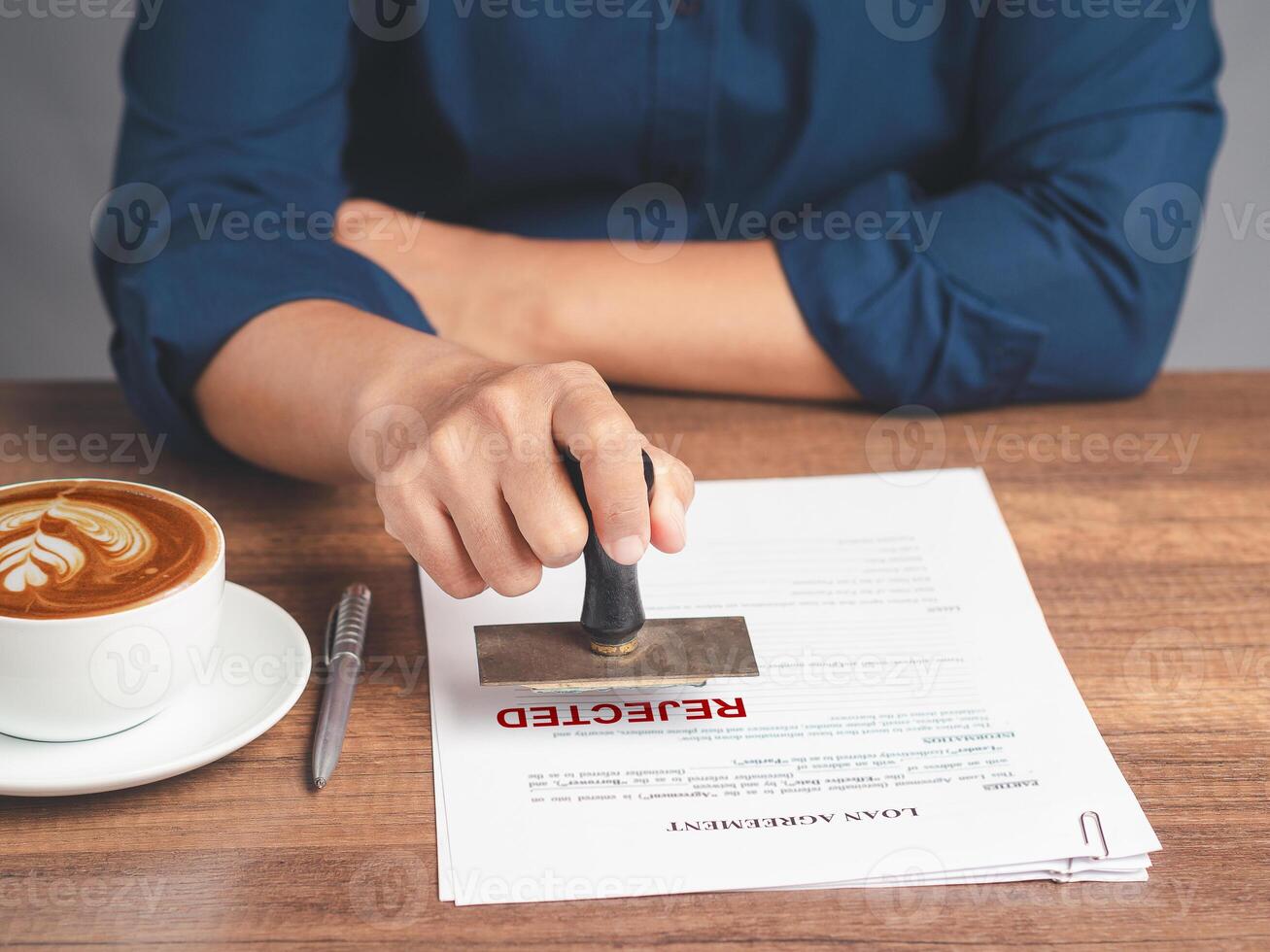 Businessman stamped for rejection on a document while sitting at the table in the office photo