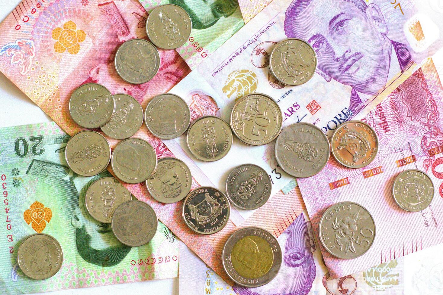 Heap of coins on top of different banknotes currency photo