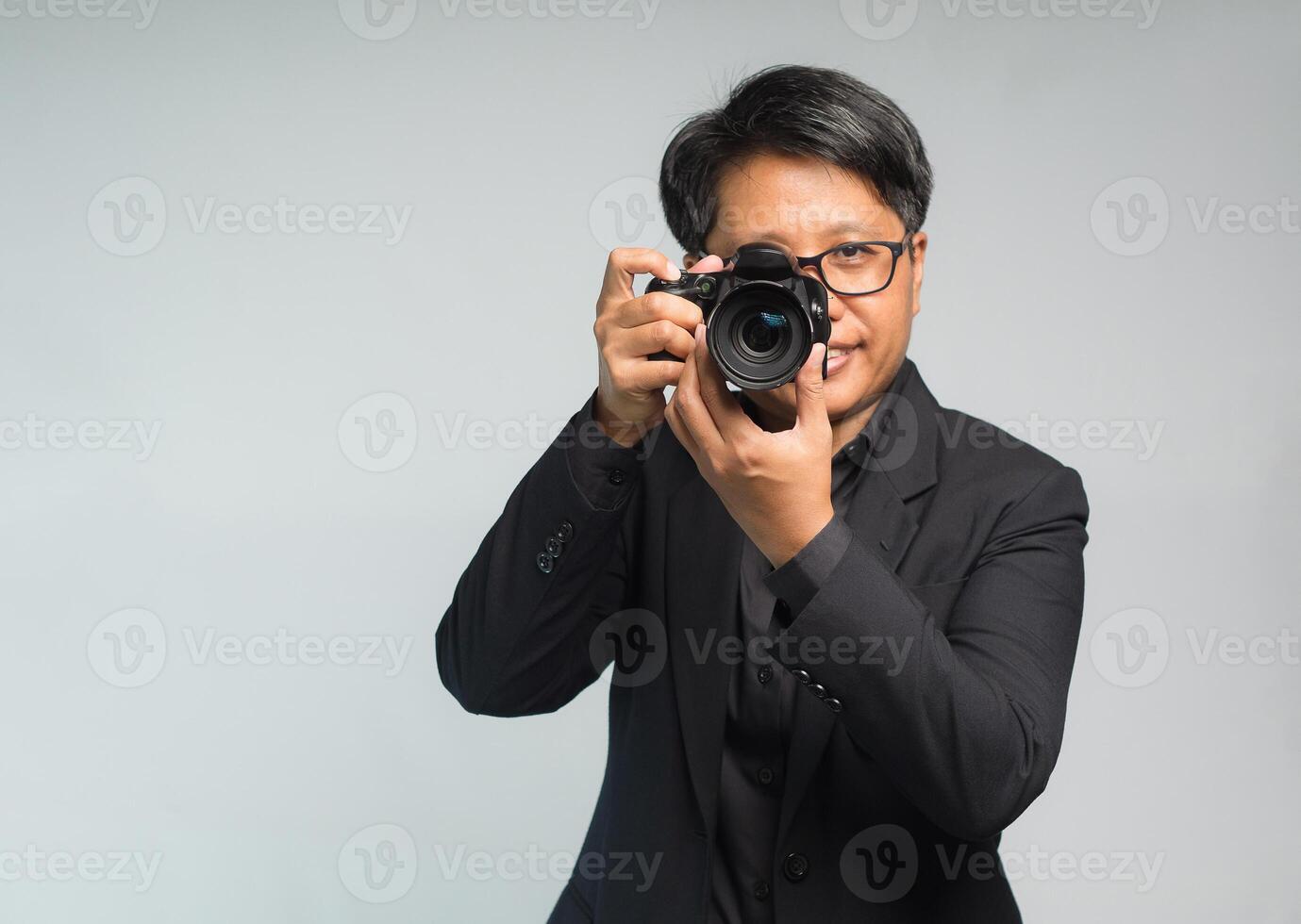 Photographer in a suit holding the digital camera while standing on a gray background photo