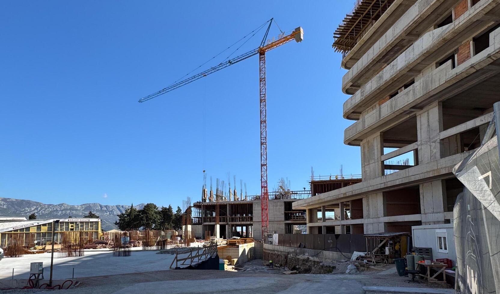 Budva,Montenegro-April 11,2025.A construction site with a tower crane and partially built multi-story concrete structure under a clear blue sky. photo