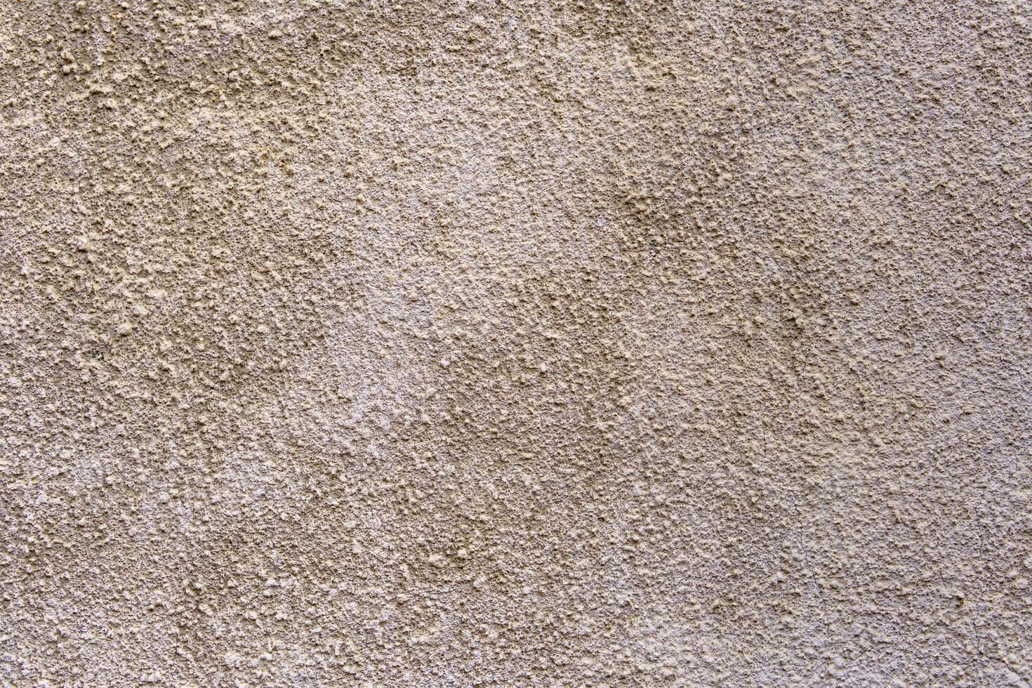 A wall with a textured surface. The wall is tan in color. The texture is rough and uneven. photo