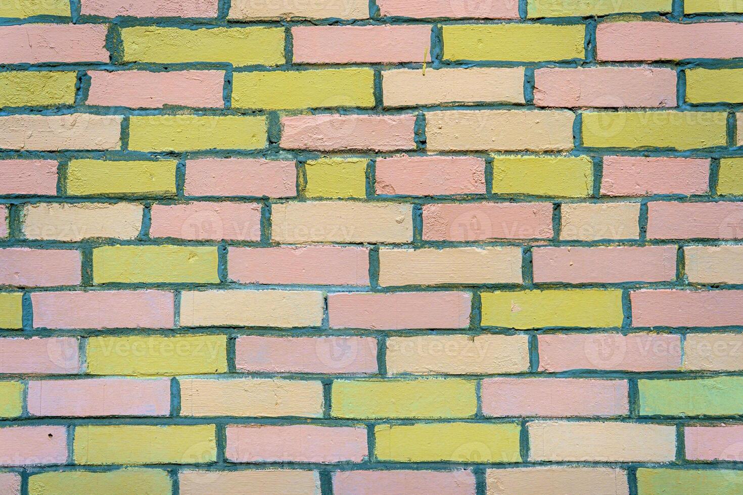 A wall made of pink and yellow bricks. The bricks are arranged in a pattern. photo