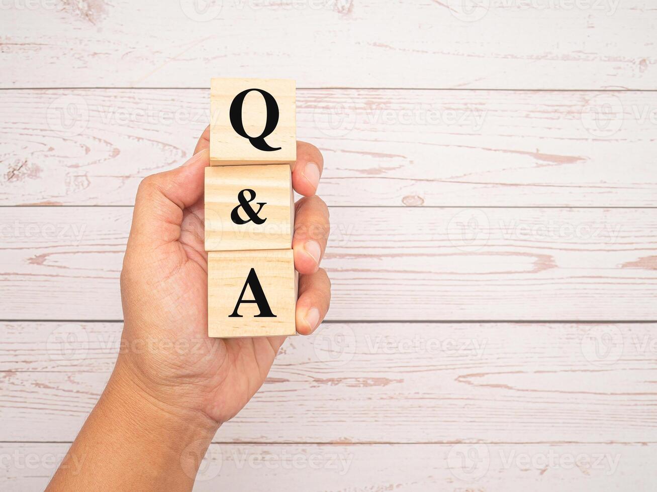 Wooden cubes with the words Q and A in hand over a wooden table. Top View. photo