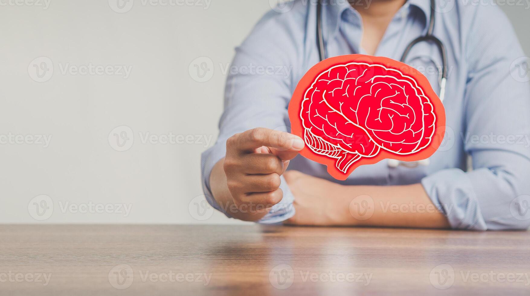Dementia concept. Doctor holding a brain symbol made from red paper while sitting at the table in the hospital. photo