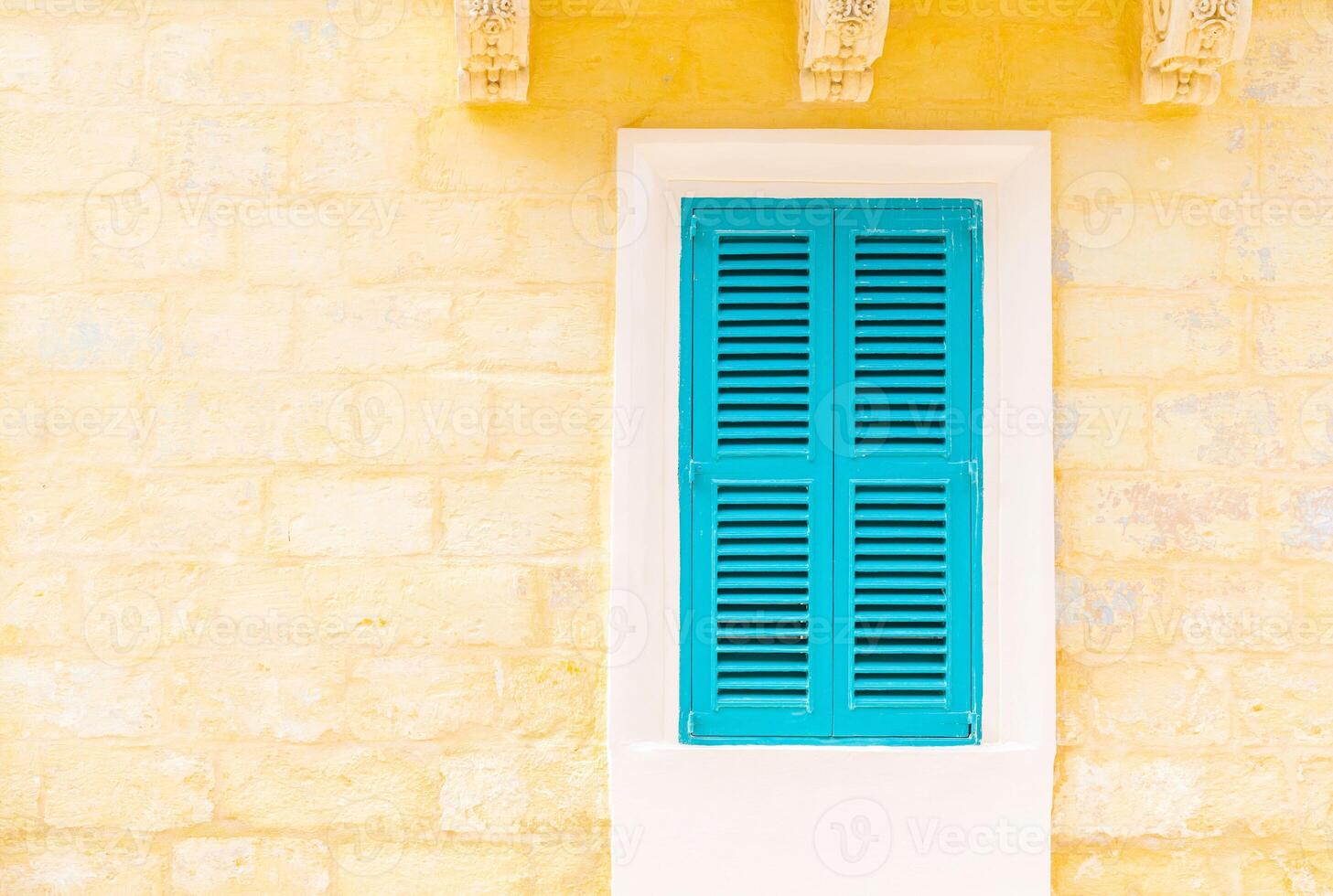Stone brick wall with a closed turquoise wooden window with shutters photo