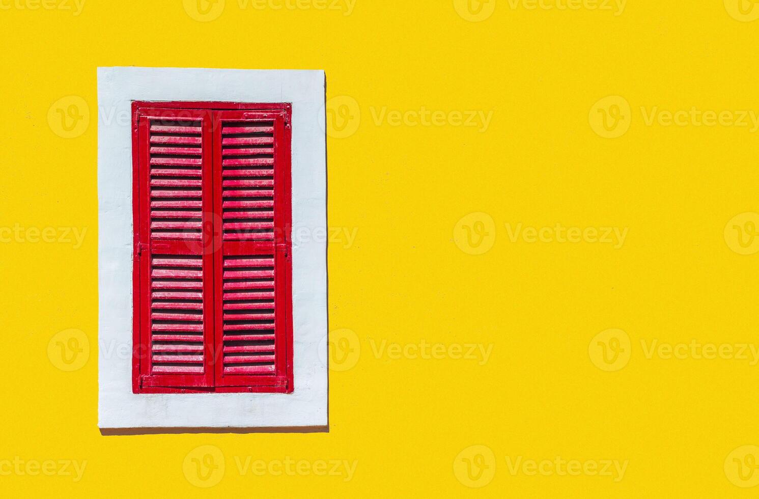 Minimalist style photo of yellow wall with red window in white frame, Murano, Venice, Italy