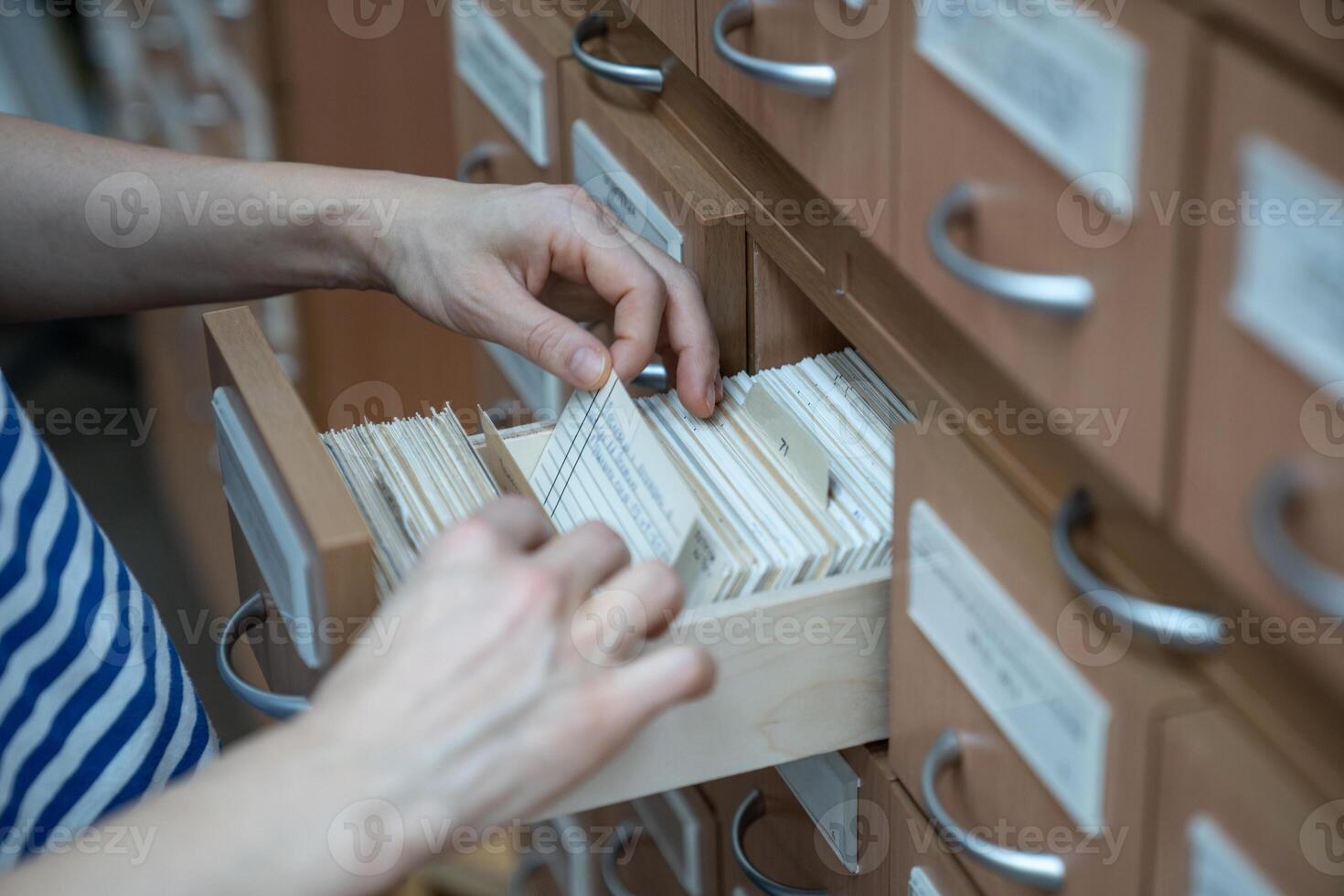 Woman student finding book cards in university card index catalog in library. photo