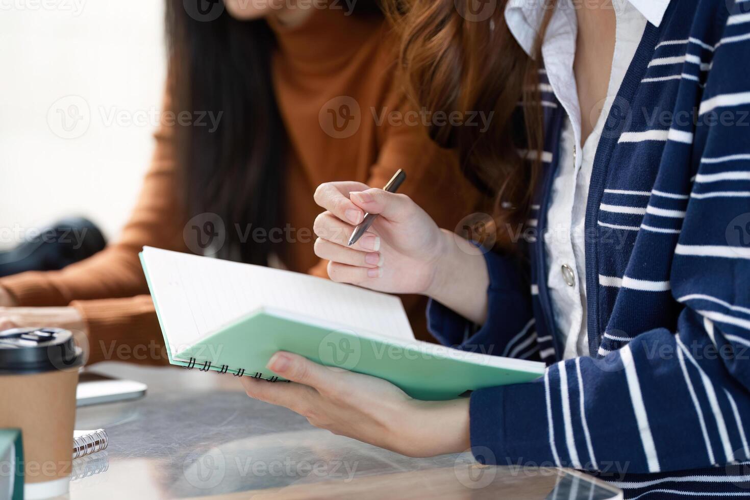 Study Session and Collaboration. Two students engaged in a productive study session with notebooks and coffee. photo