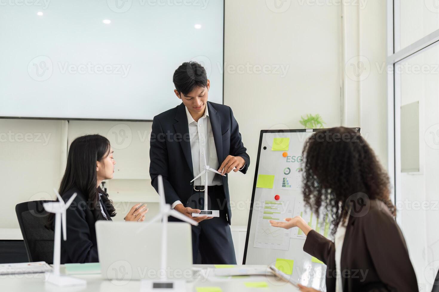 ESG Presentation and Renewable Energy Insights. A speaker presents sustainable initiatives using a model in a board meeting. photo