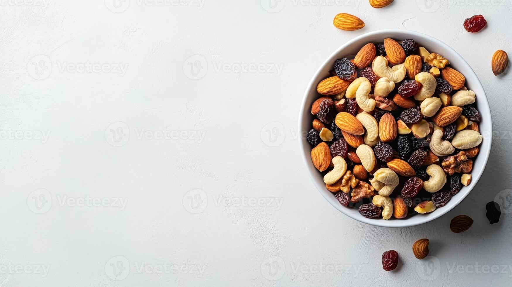 Bowl filled with assorted nuts and dried fruits on a white surface photo