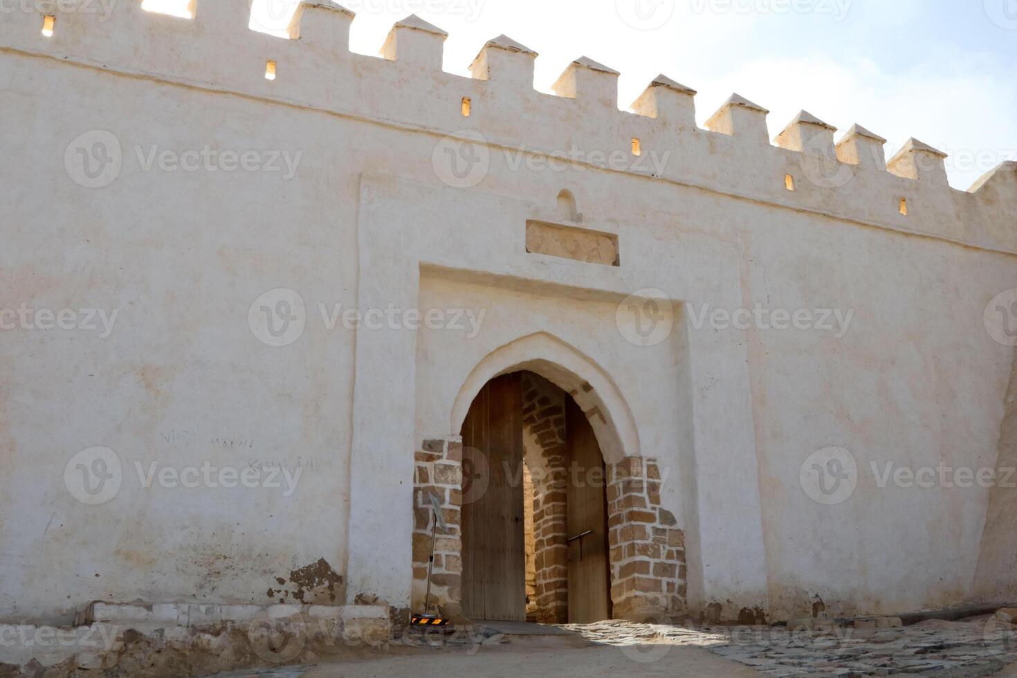 Main wooden entrance to agadir oufella fortress with archway and brick details morocco photo