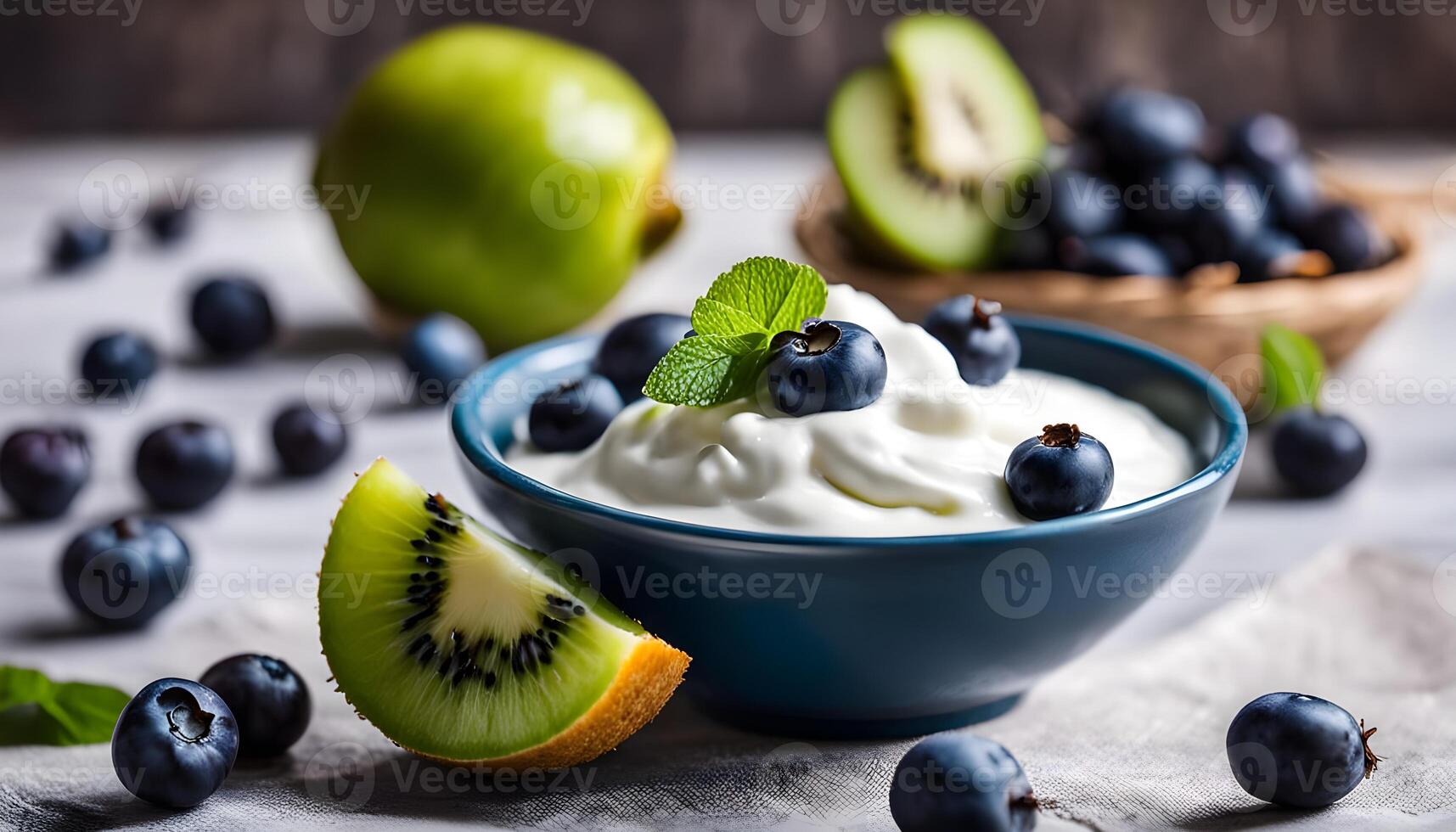 Natural light photo of Greek yogurt and fruit bowl, featuring blueberries and kiwi, served with a sprig of mint and a honey drizzle