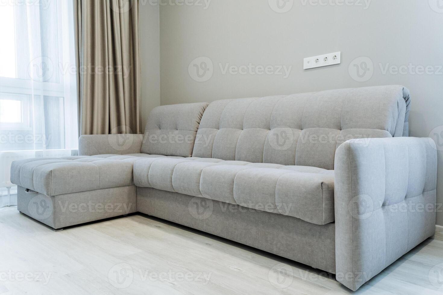 In a cozy living room, a large sectional couch is comfortably positioned next to a window, allowing natural light to brighten up the space, perfect for relaxation and leisure activities photo
