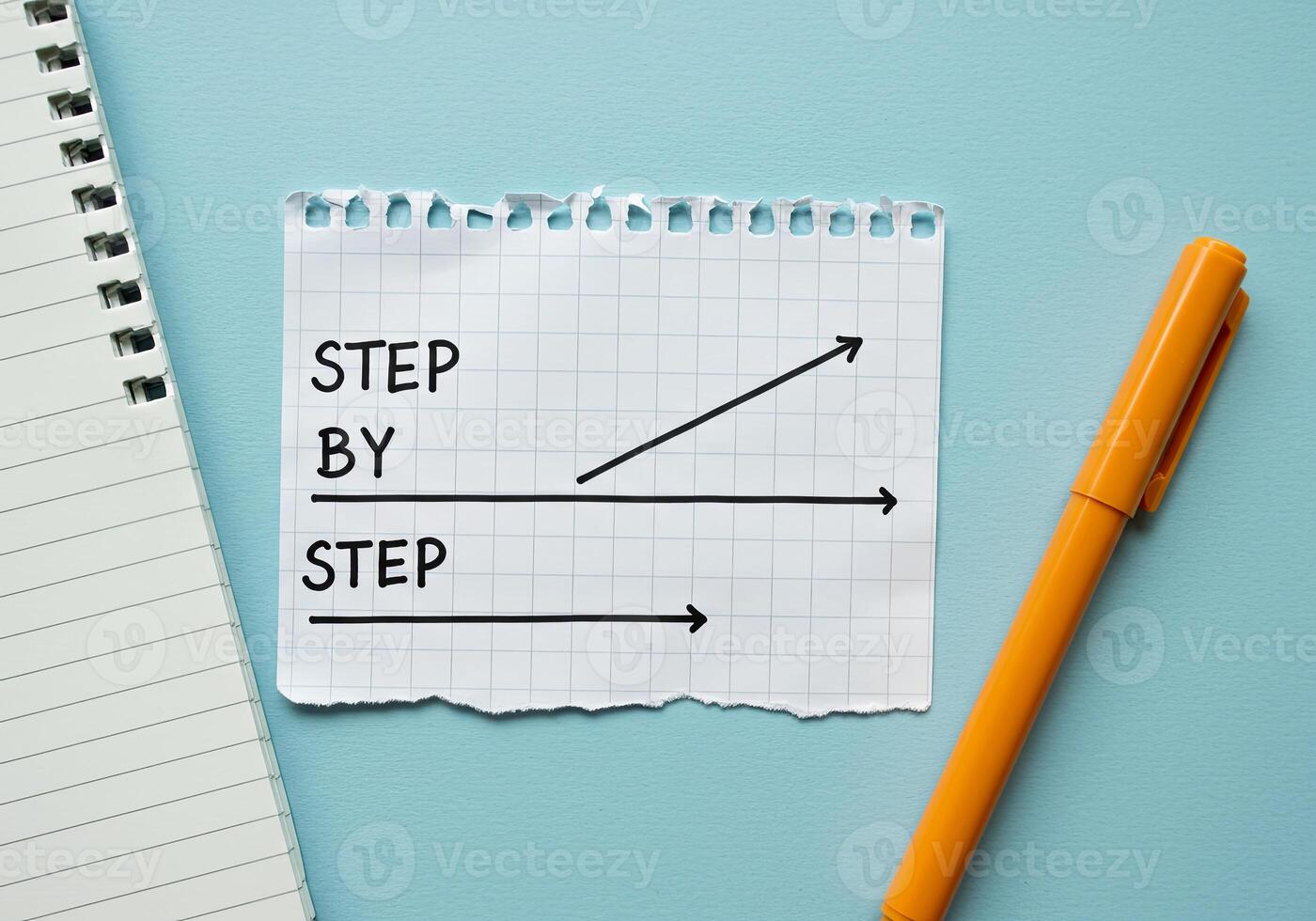 Step by step concept with arrow on paper, notebook and pen on blue background photo
