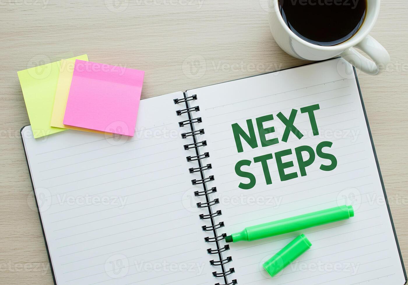 Next steps on notebook with pen and coffee cup photo