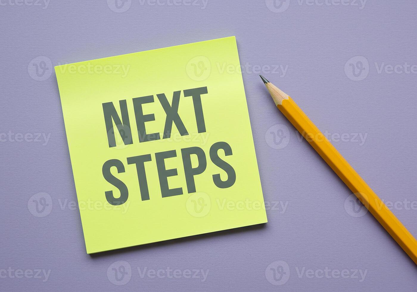 Next steps on a yellow sticky note with a pencil on a purple background photo