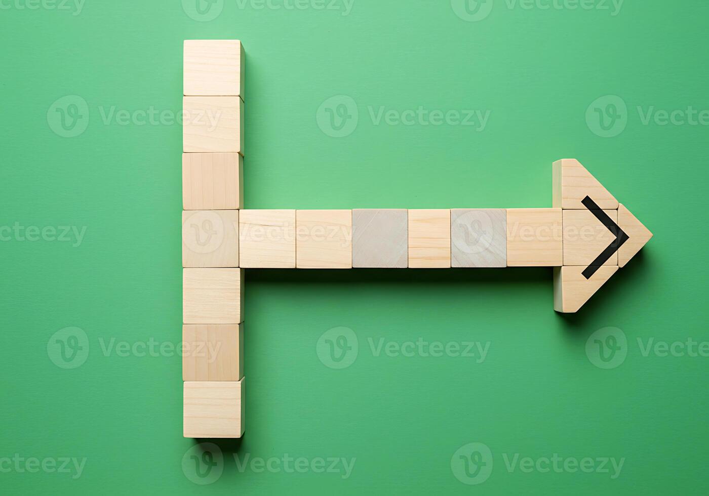 Wooden blocks with arrow pointing to the right on green background photo