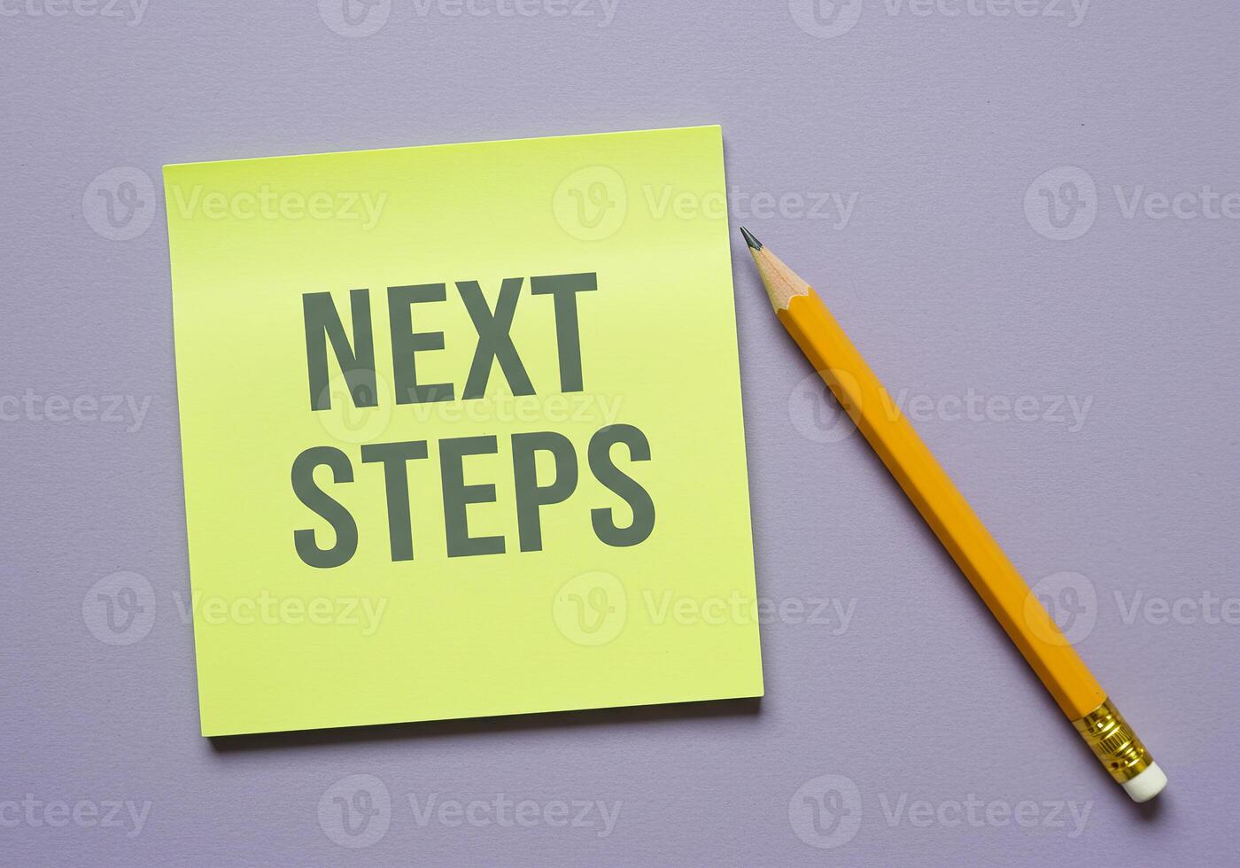 Next steps on yellow sticky note with pencil on purple background photo