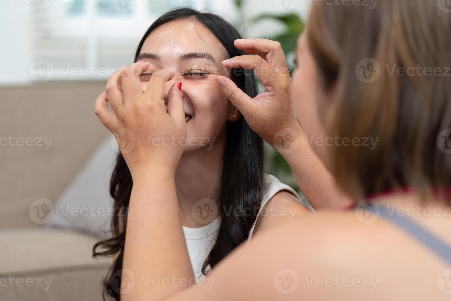 Makeup Application and Self-Expression. A woman enjoys a creative makeup moment with a friend by her side. photo