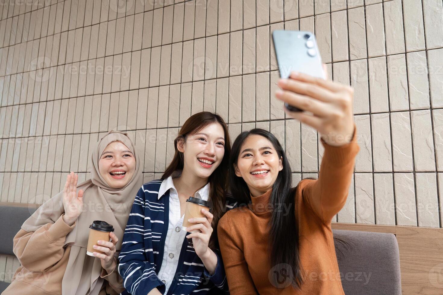 Social Connection and Selfie Moments. Three friends capturing fun memories while enjoying coffee at a cafe. photo
