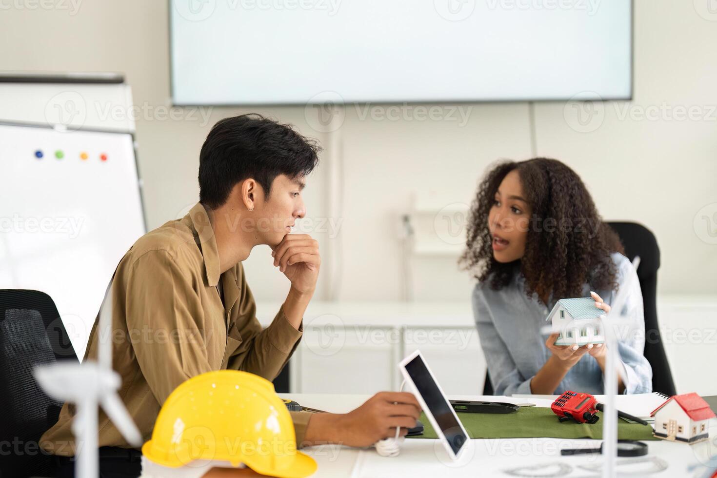 Innovative Design and Strategy. Team members evaluating sustainable architecture ideas using models in a creative meeting. photo