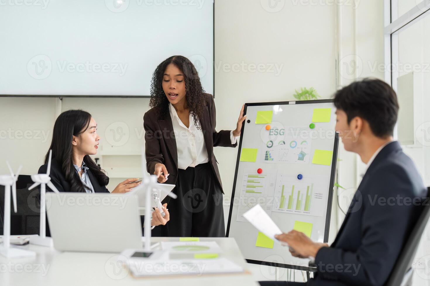 ESG Insights and Collaborative Strategies. A professional setup featuring an engaging woman discussing ESG objectives with her team. photo