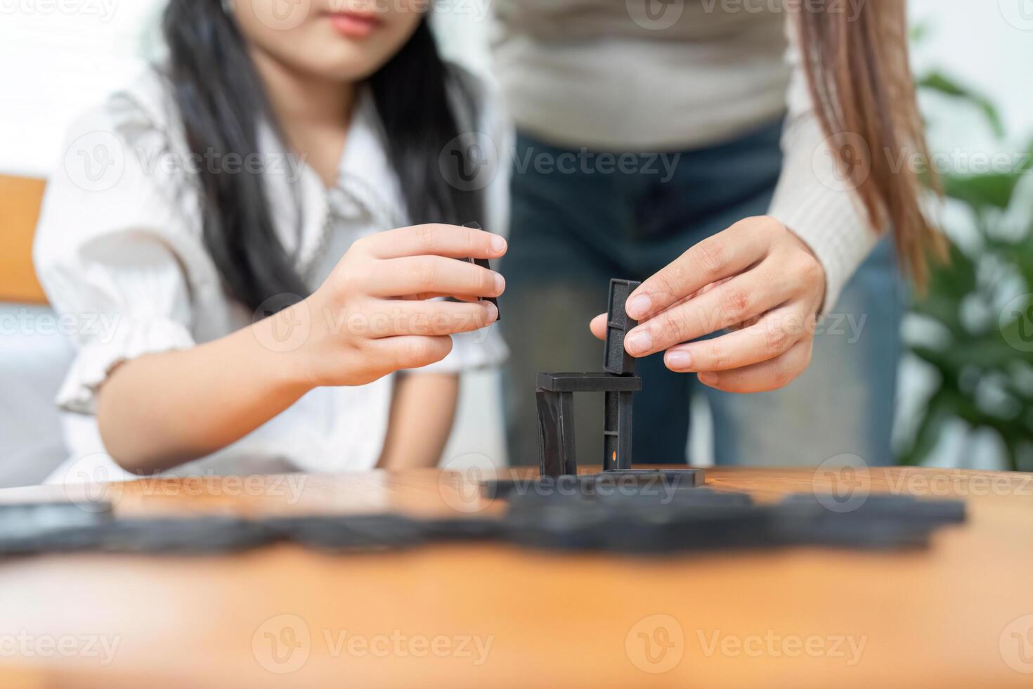 Togetherness in Learning. A mother helping her daughter build strategies while playing with dominos. photo