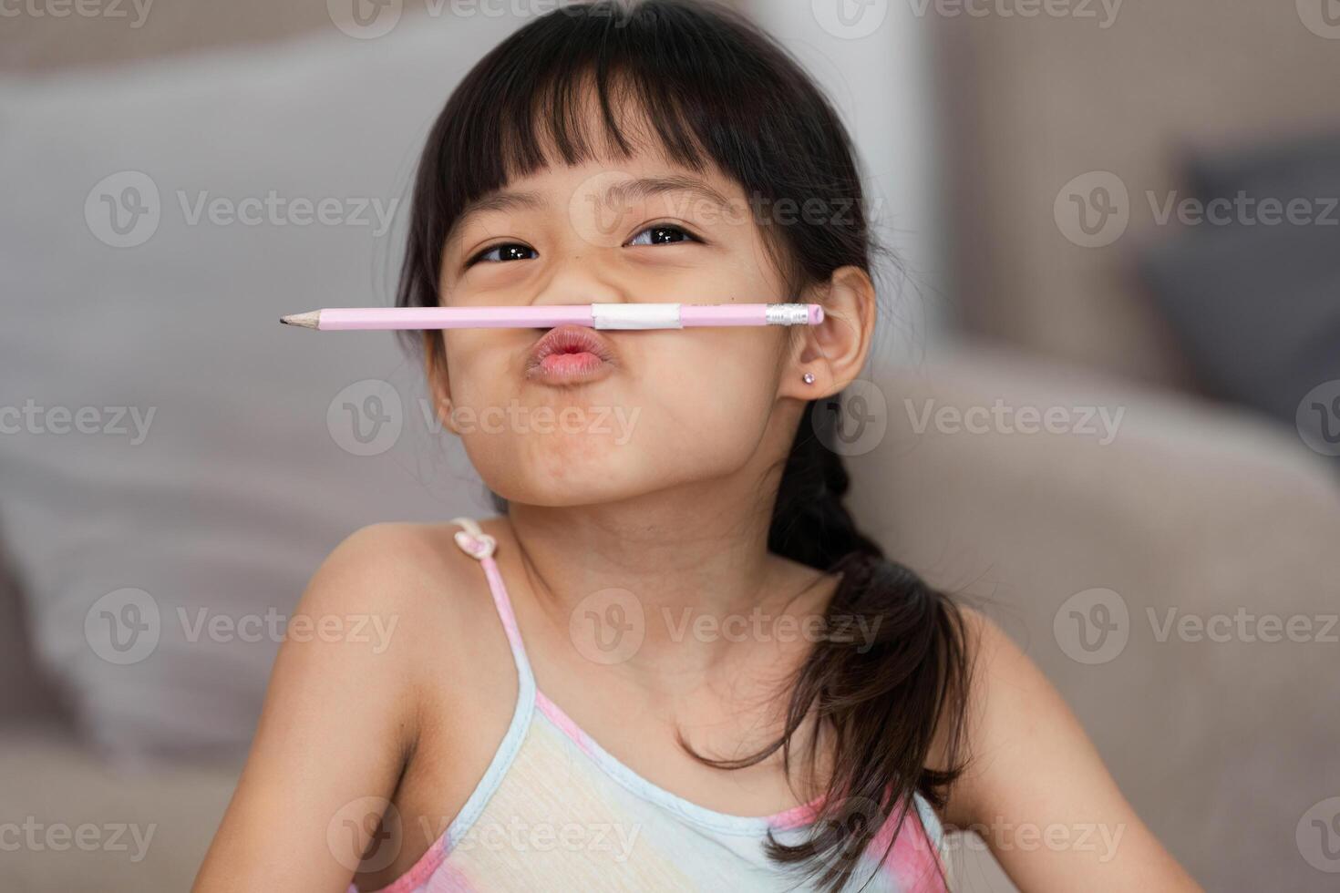 Silly Moments and Imagination. A girl making funny faces with a pencil, showcasing her playful spirit during art time. photo