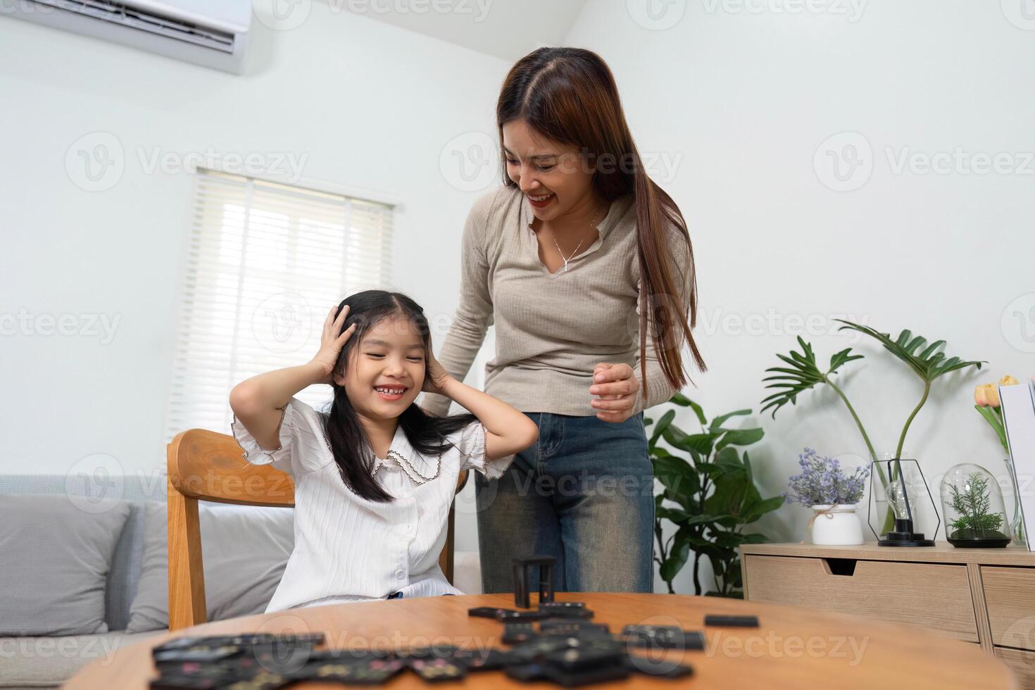 Joyful Play and Learning. A playful moment between a mother and her daughter brings smiles and laughter during game time. photo