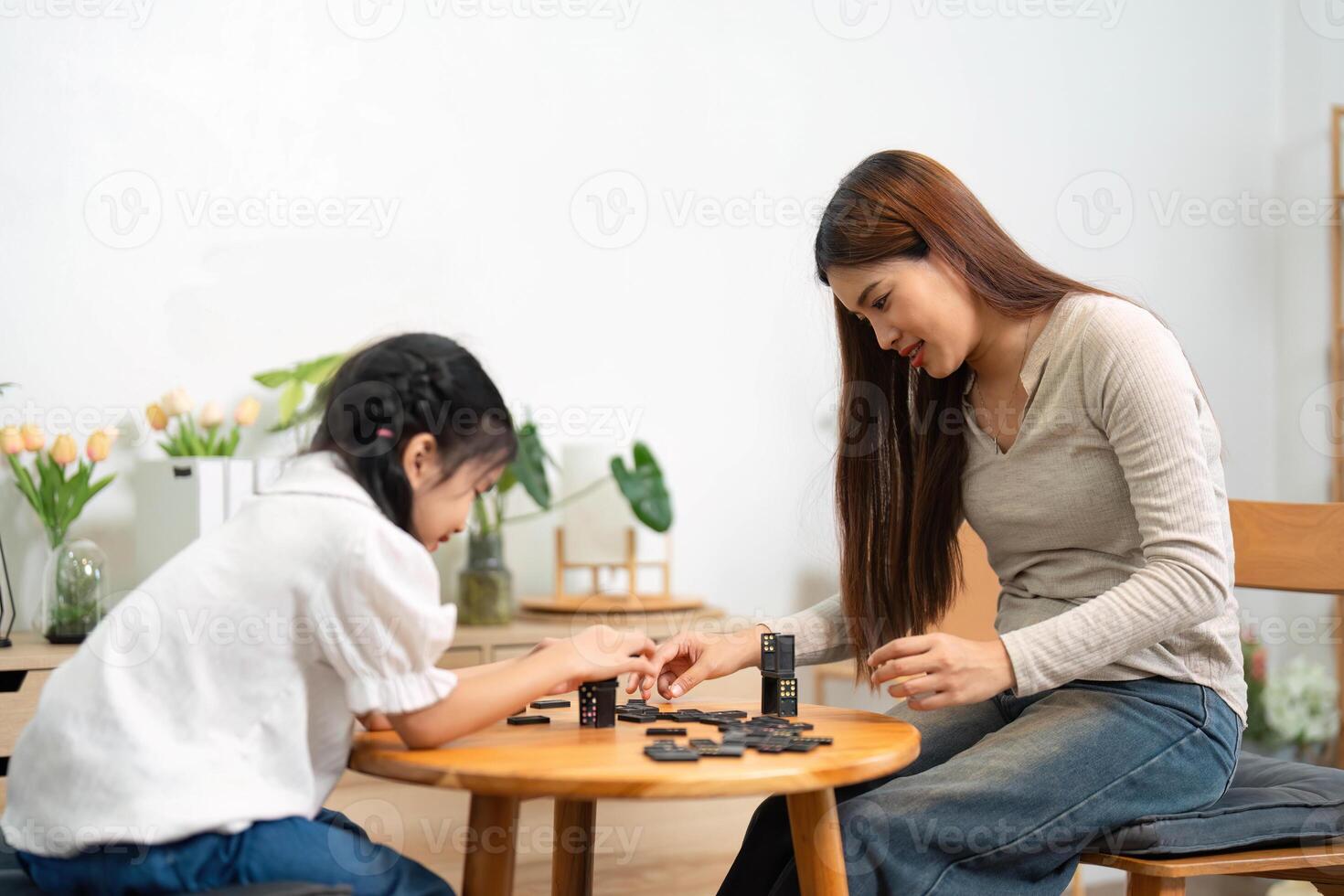 Quality Time and Fun Learning. A girl focused on a board game while playing with her mother, creating lasting memories together. photo