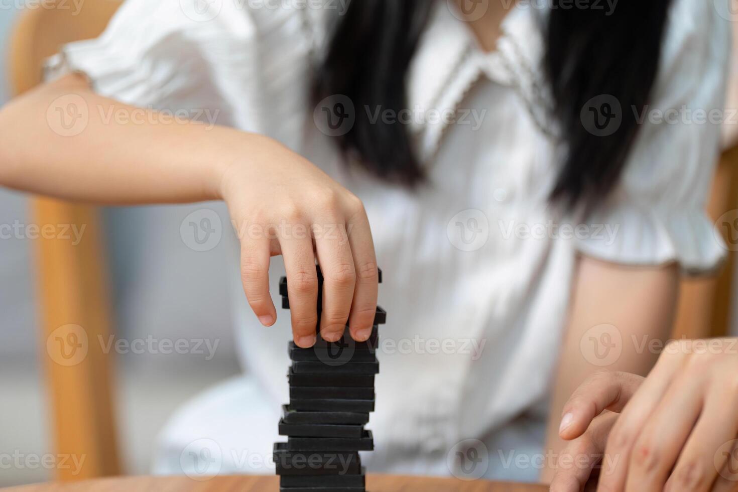 Family Bonding and Growth. A child and her mother engage in a fun stacking game, enhancing skills together. photo