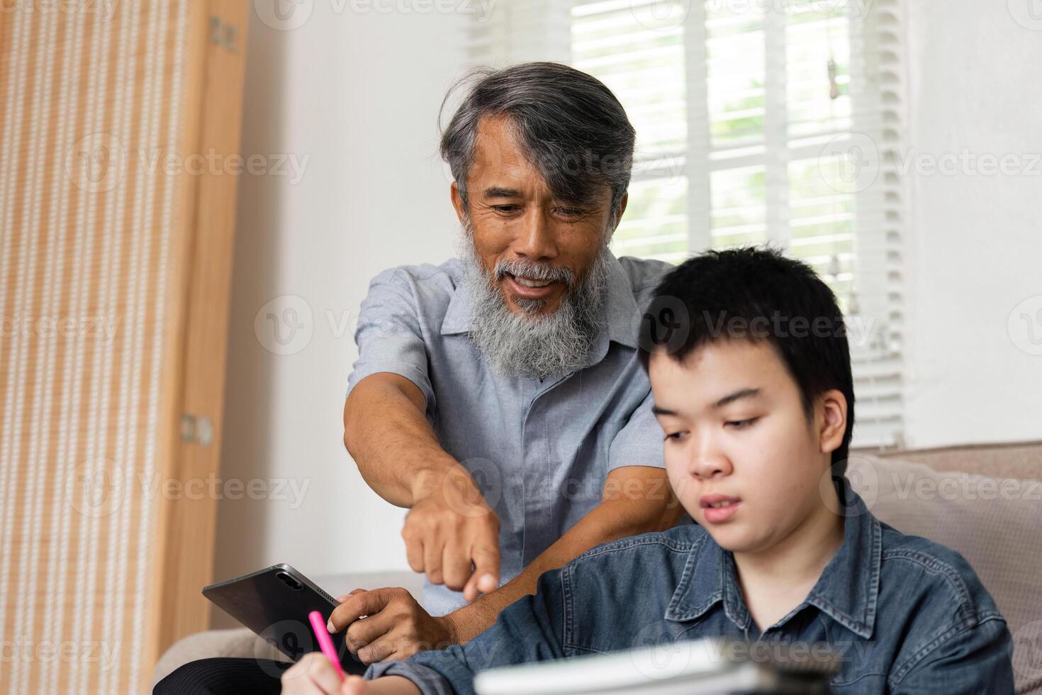 Interactive Learning Experience. A grandfather enthusiastically engages with his grandson during a study session. photo