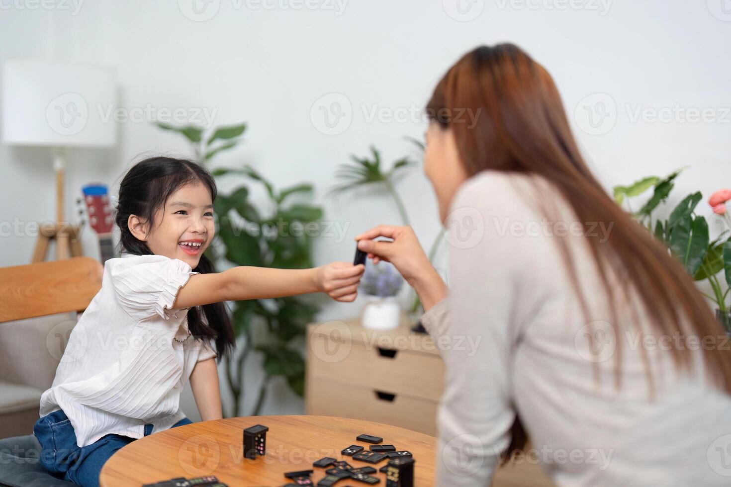Family Bonding and Playtime. A young girl sharing a joyful moment with her mother while playing a board game. photo